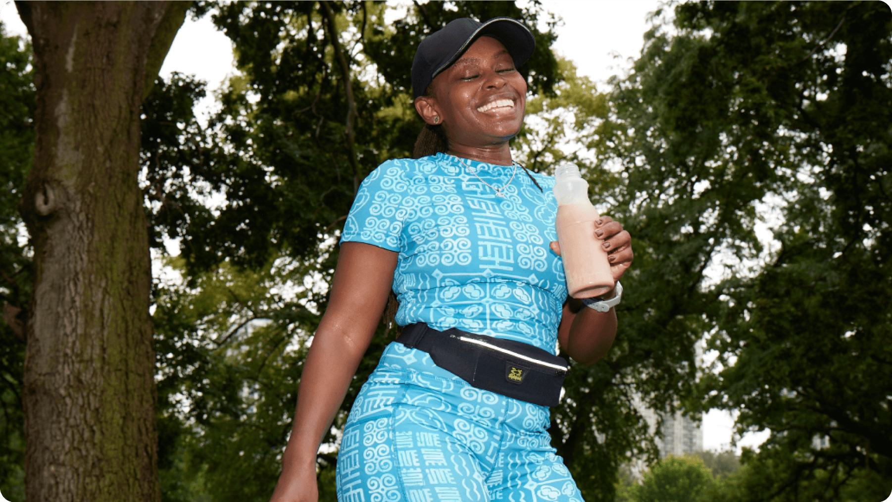 A female with a bright smile, holding a bottle of chocolate milk.